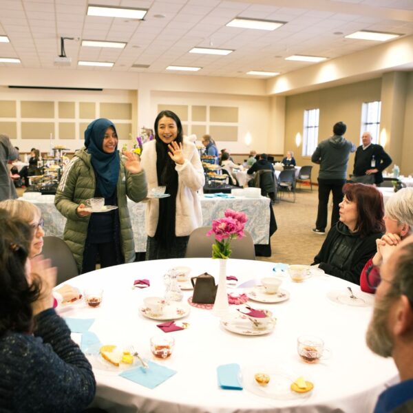 Faculty and staff greet each other at a table during High Tea at Newman University.