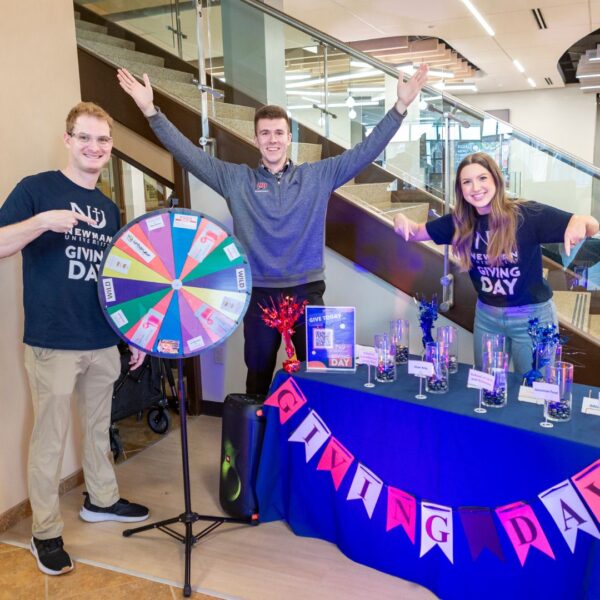 Staff members smile from the Giving Day student booth