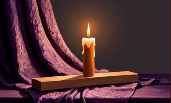 Single Candle burning on block wood, with purple cloth drapped behind and under it