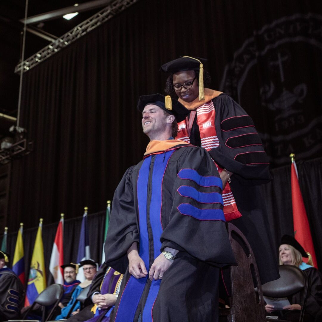 Lucas receives his ceremonial hood from Brent, director of the DNAP program.