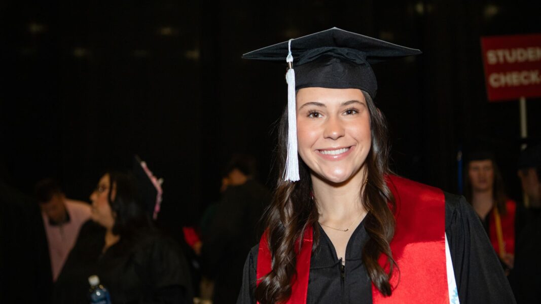 Kindred smiles in her graduation cap, gown and athletic stole on graduation day.