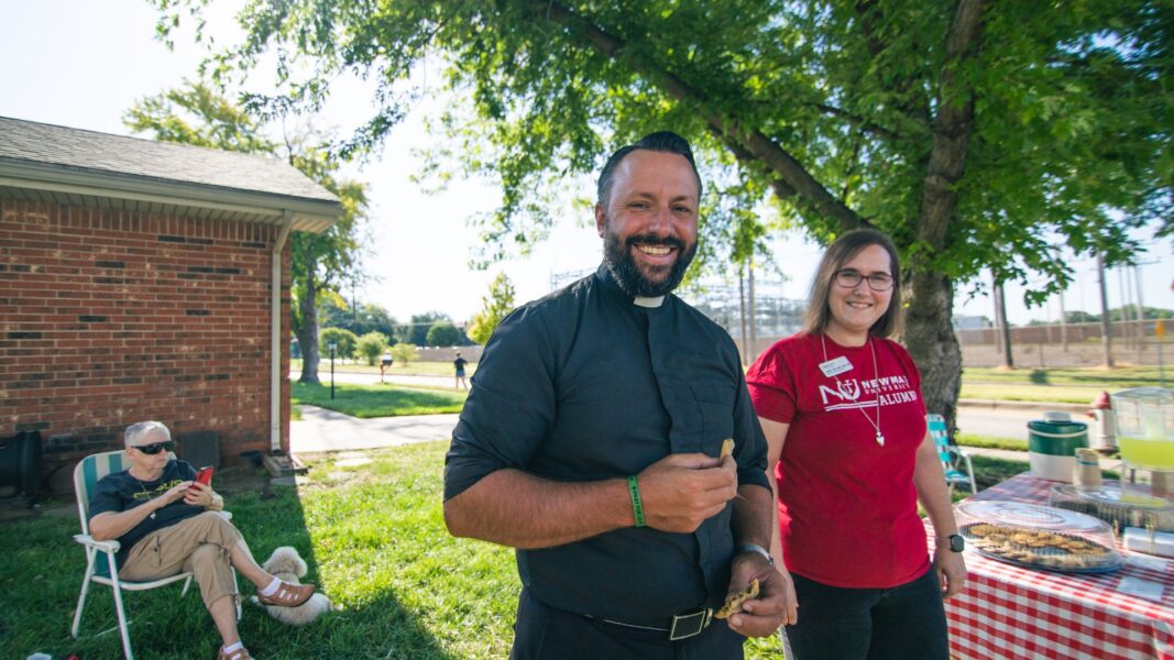 Father Ed Herzog, Newman chaplain, stands at a picnic table with ASC sisters during student move-in day.