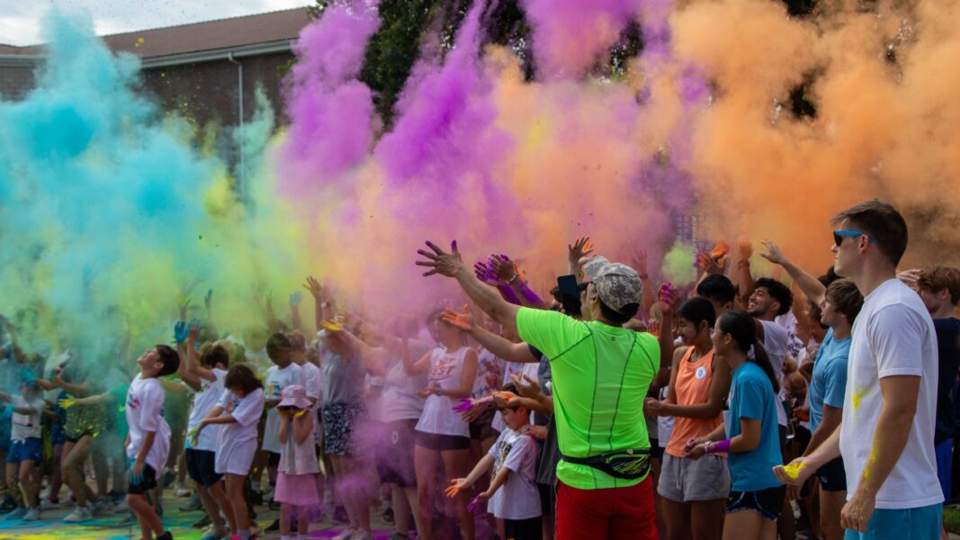 Students, families and friends throw colorful powder at the start of the 2024 Color Run.