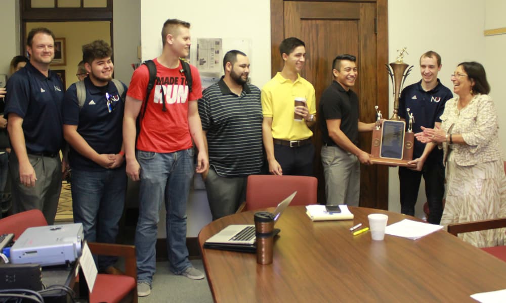 Murphy (far left) and 2016-17 men's bowling team presents the program's first-ever 
Mid-States Championships title trophy to former President Noreen Carrocci