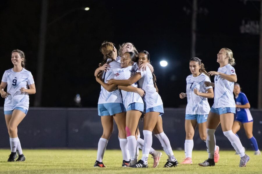 Four members of the women's soccer team embrace in a hug after a win. (Courtesy photo: Richard Rico)