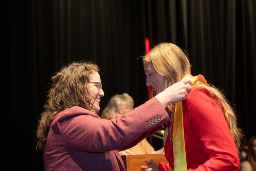 Tyrell gives a student their stole during the School of Healthcare Professions pinning ceremony in May 2025.
