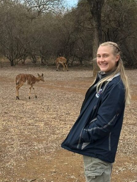 Koenig in Eswatini, posing in front of deer.