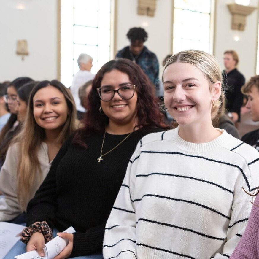 Students smile from the pews of St. John's Chapel.