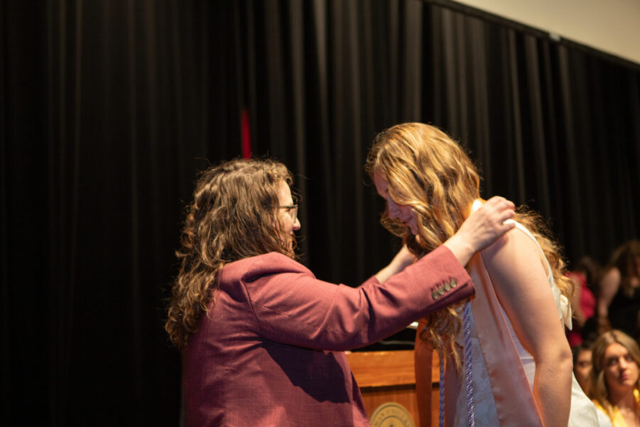 Tyrell places graduation stole on Hughes at graduation
