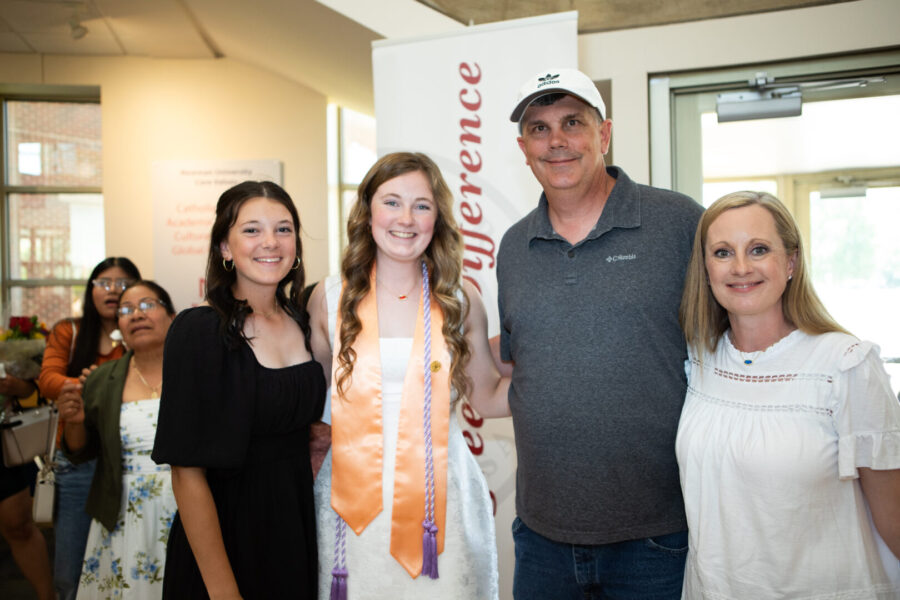 Hughes with family members, posed in front of Newman banner