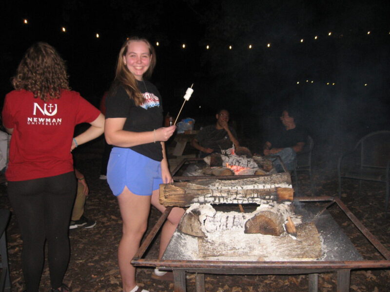 Students gather around the campfire to roast s'mores.