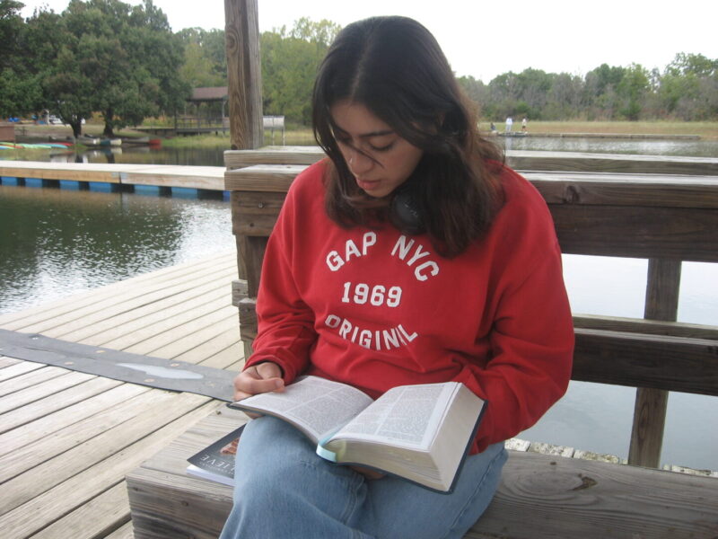 A student reads her Bible by the pond.