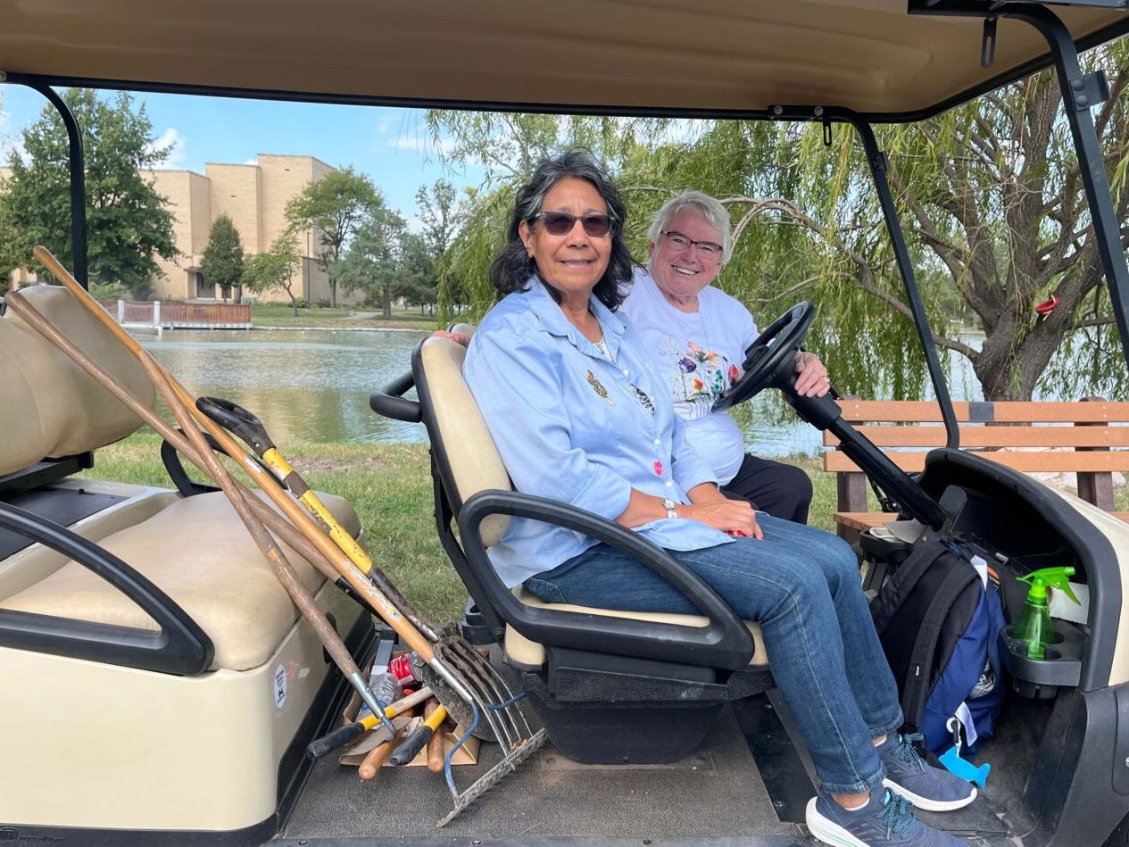 Pictures Smith and Mendoza in golf cart with gardening supplies in the back