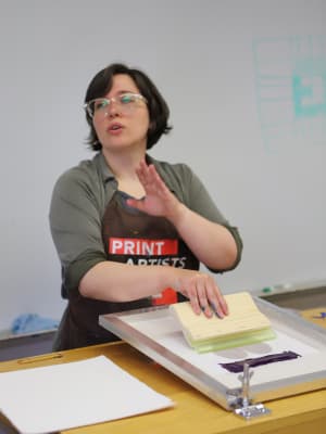 Emily Ritter, Newman University Digital Design Program Director talking with Students in a screen printing class
