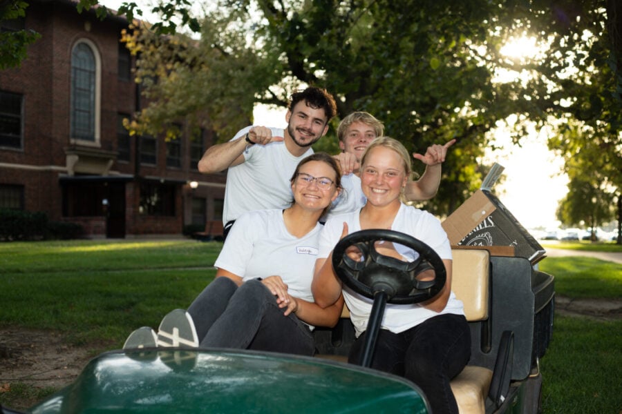 Pictures Pearson with others on a golf cart on campus.