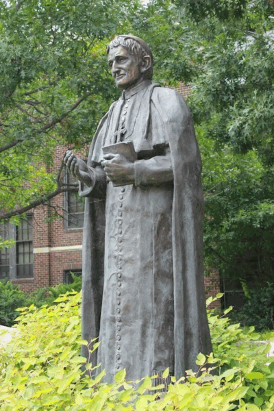 Shows the statue of St. Newman on campus grounds
