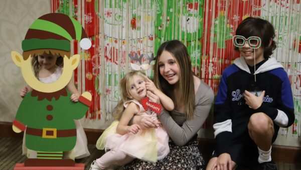 Guests snap cheery holiday photos with an elf-themed backdrop.