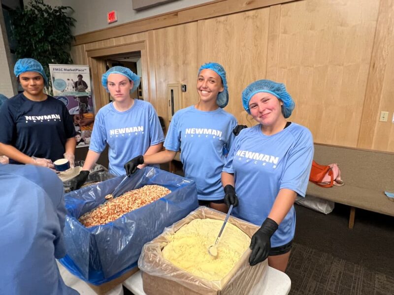 Newman students smile while packing meals for Feed My Starving Children.