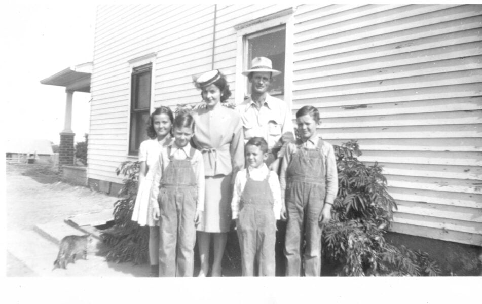 Black and white family photo of Father Rother and Sister Marita as children with rest of Rother family.