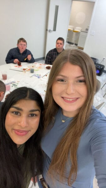 Ahmed and Adams posing for picture with event guests in background