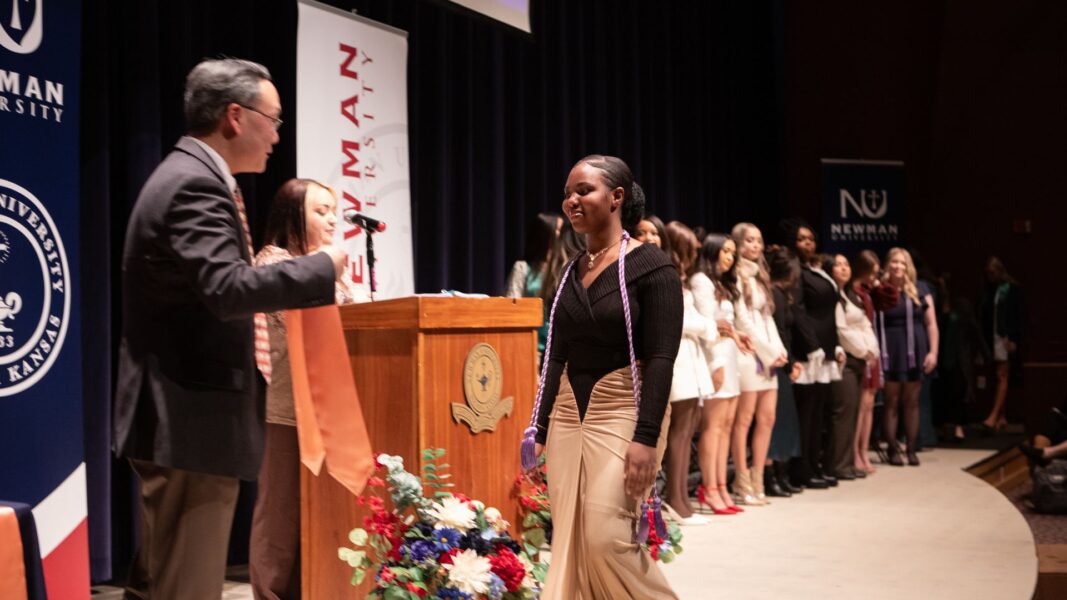 A nursing graduate crosses the stage to accept her stole and nursing pin.