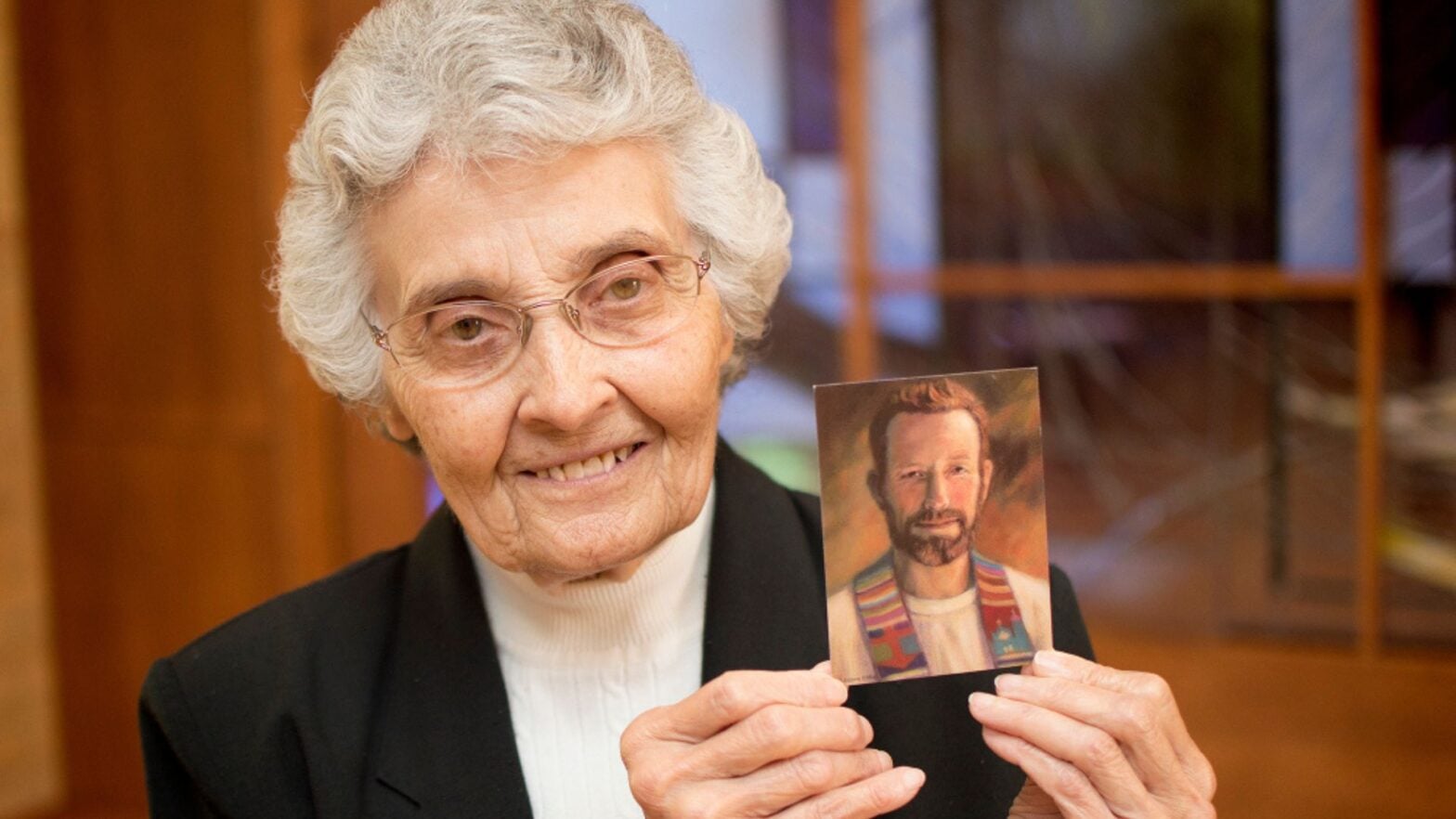 Sister Marita holds a prayer card of her brother, Blessed Father Rother. (Photo credit: The Catholic Advance)