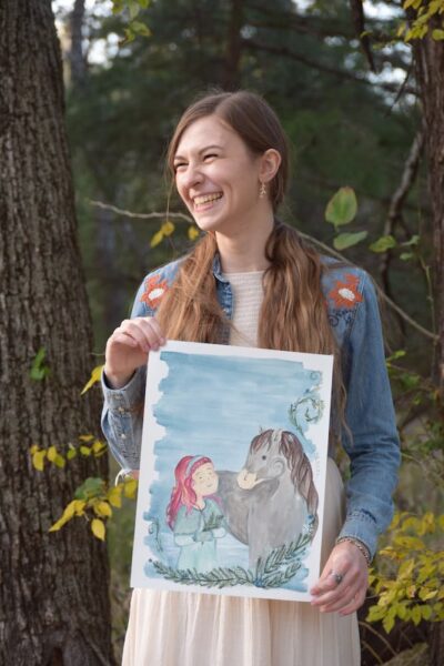 Strickbine holds an illustration of two of her characters, Joy and Mabel.