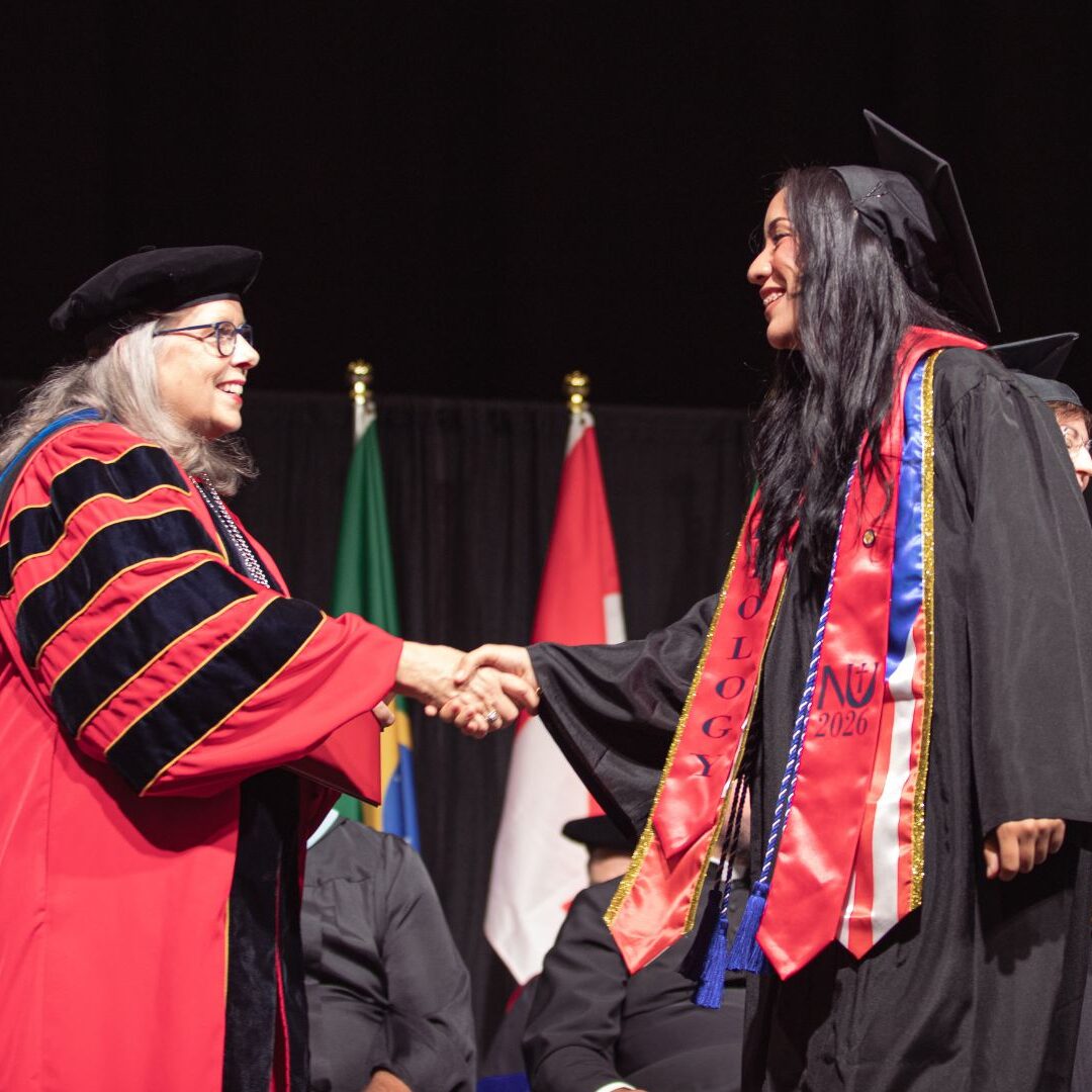 A graduate shakes President Jagger's hand as she crosses the commencement stage.