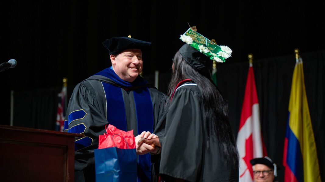 Stout shakes Smith's hand as she accepts her award on stage.