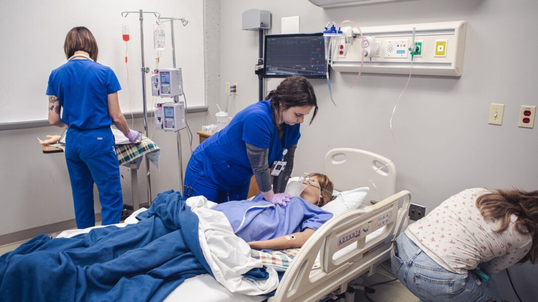 A student performs CPR on the talking, blinking and breathing simulation mannequin.