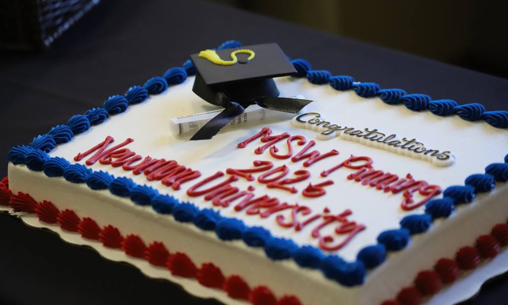 A celebratory cake reads "Congratulations MSW Pinning 2026 Newman University."