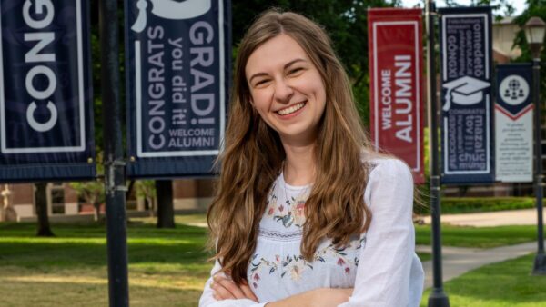 Strickbine stands in front of the pole banners she helped design at Newman University.