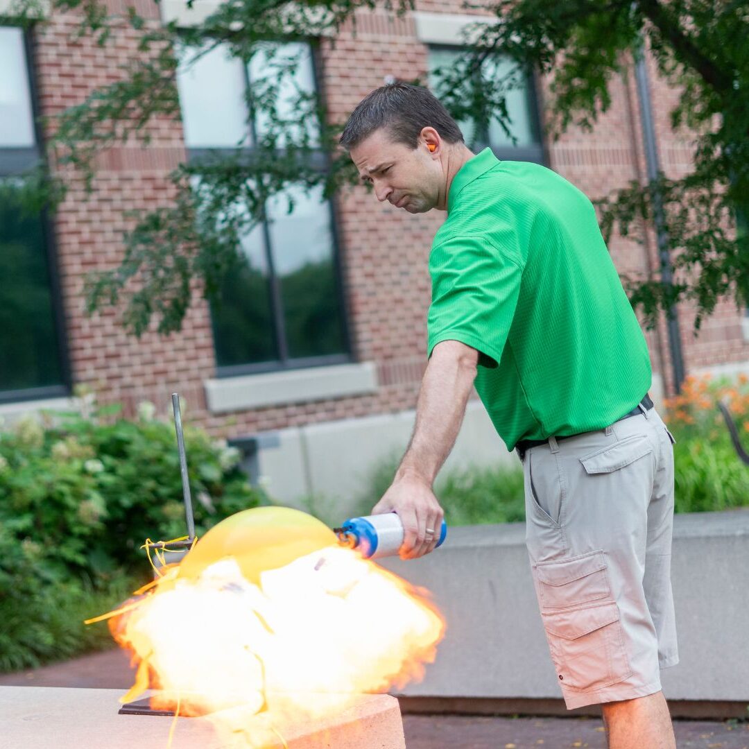 Huschka explodes a balloon outside the Bishop Gerber Science Center.
