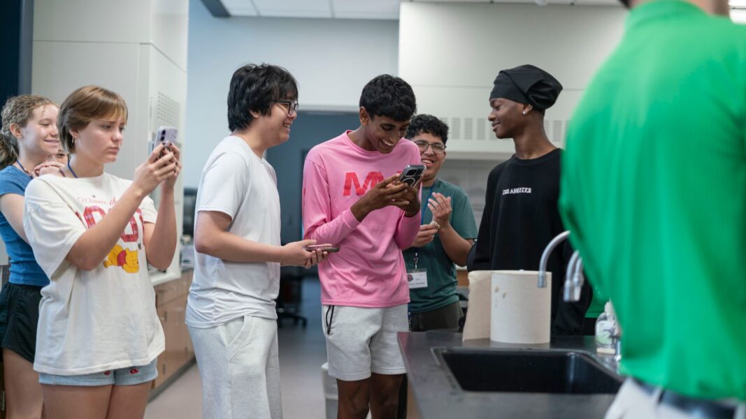 ISSP campers film some of the excitement on their phones while witnessing an experiment with fire.