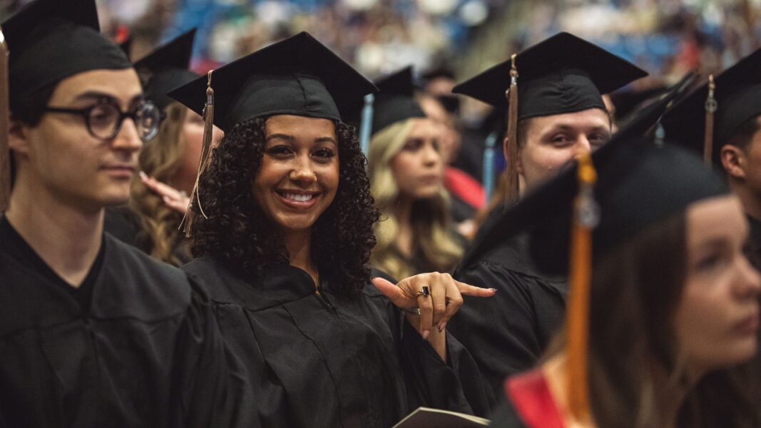 A Newman graduate shows off the Newman Jet hand sign.