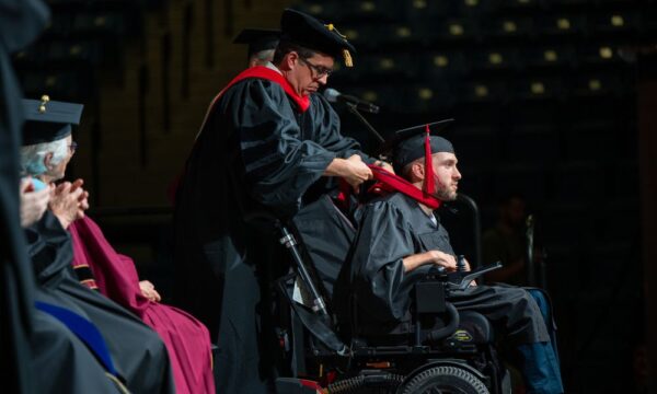 Papsdorf hoods a Master of Theology student during Newman's 2026 commencement ceremony.