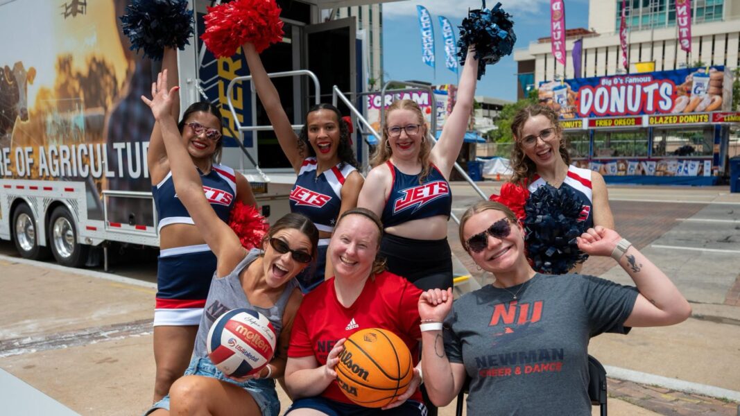 The following group represented Newman University Athletics at the 2026 Riverfest: (Back row) Real, second from the right, and fellow members of the Newman cheer and dance team; (Front row, left to right) Volleyball coach Tori Provencio, women's basketball coach Amy Briggs and cheer and dance coach Paige Roubideaux